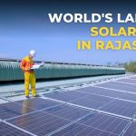 Picture of a construction worker standing in a solar power plant. Image also has a text heading which says worlds largest solar park in rajasthan